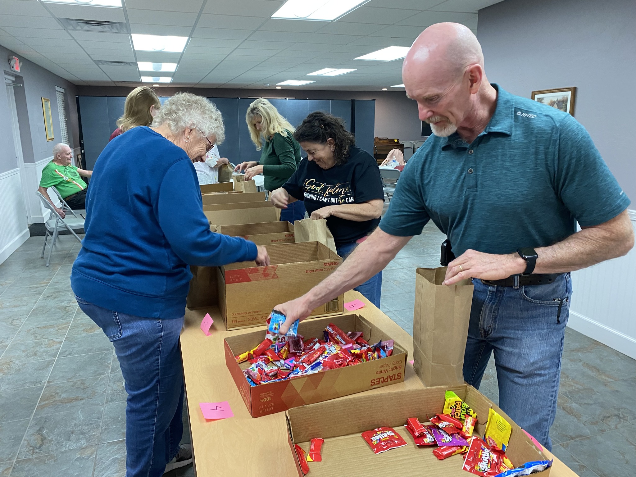 Volunteers filling paper bags with assorted wrapped candies